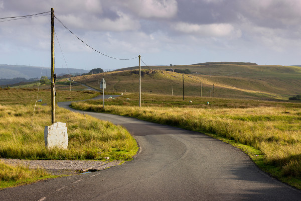 Postes de telégrafo em uma estrada rural galesa em Brecon Beacons, no Reino Unido.