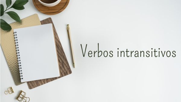 Caderno de anotações ao lado de um lápis sobre uma superfície plana com o escrito “verbos intransitivos”.