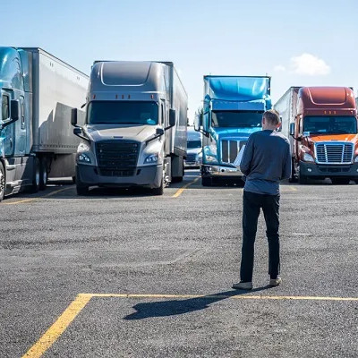 homem parado encarando caminhões