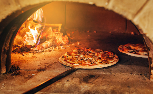 Pizza italiana sendo feita em um forno a lenha, um dos principais tipos de pizza na história da pizza.