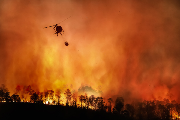 Helicóptero jogando água sobre um incêndio florestal (queimada), um dos principais problemas ambientais.