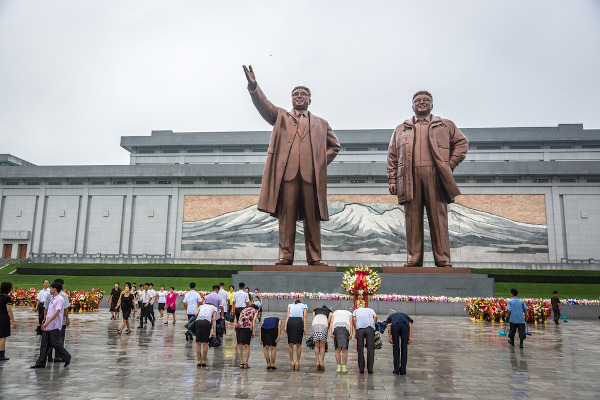 Estátuas de Kim Il-sung (à esquerda) e Kim Jong-il (à direita) sendo reverenciadas em Pyongyang, Coreia do Norte. [3]