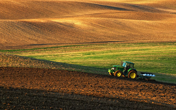 Máquina agrícola em um campo, uma alusão aos estudos da geografia agrária.