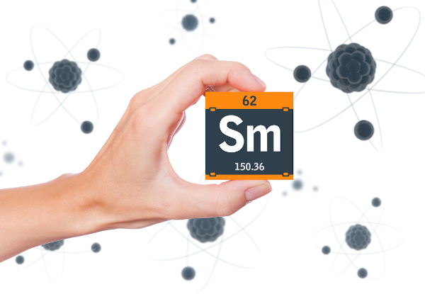 Pessoa segurando um cubo preto com laranja com o símbolo, o número atômico e a massa do elemento químico samário.