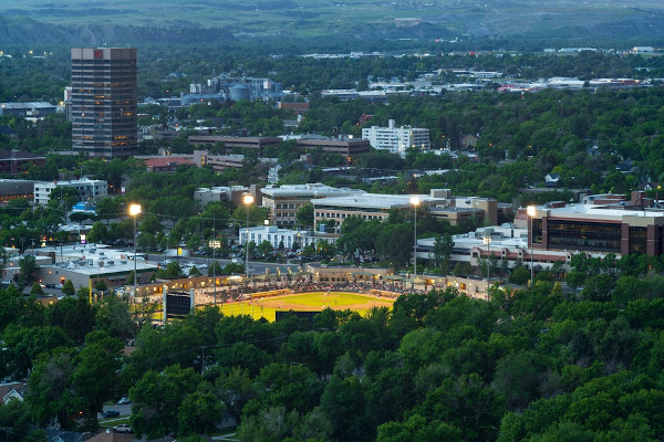 Vista da cidade de Billings, em Montana, com um estádio e edifícios entre muitas árvores.