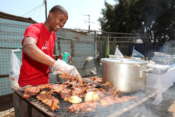 Homem sul-africano assando carne, um dos elementos característicos da cultura da África do Sul.