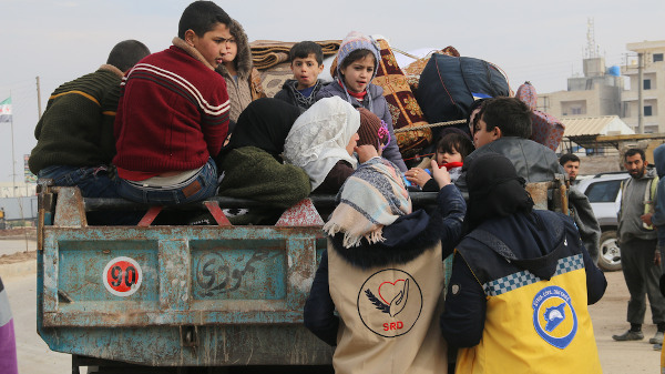 Voluntárias de grupos pacificadores distribuem medicamentos a crianças refugiadas sírias em caminhão.[1]
