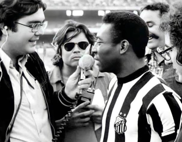 Foto em preto e branco do Faustão de óculos entrevistando o Pelé com a camisa do Santos. 