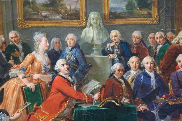Pintura mostrando pessoas reunidas no salão literário da Madame Geoffrin durante a leitura de uma das obras de Voltaire.