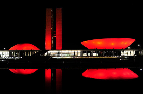 Prédio do Congresso Nacional, em Brasília, iluminado de vermelho no mês de dezembro, parte da campanha Dezembro Vermelho.
