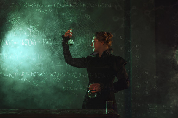 Mulher segurando frasco representando Marie Curie, em texto sobre filmes para assistir nas férias escolares.