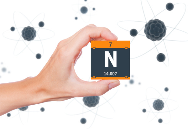 Pessoa segurado um cubo com o símbolo, a massa atômica e o número atômico do elemento químico nitrogênio (N).