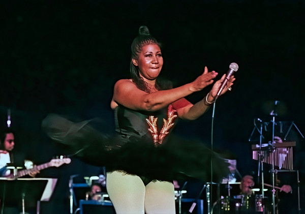 Aretha Franklin em palco e segurando microfone
