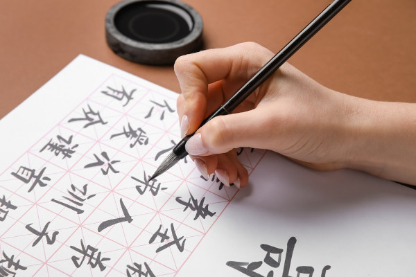 Pessoa escrevendo com o sistema de escrita chinês, parte importante da história da escrita.