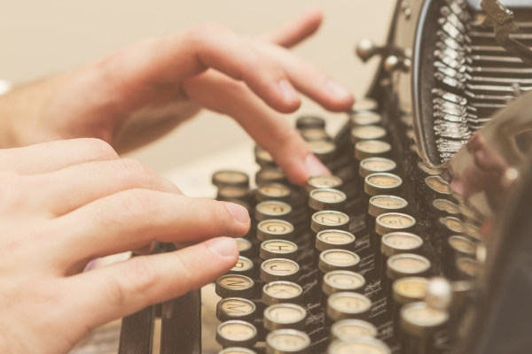 Pessoa digitando em uma máquina de escrever, parte importante da história da escrita.