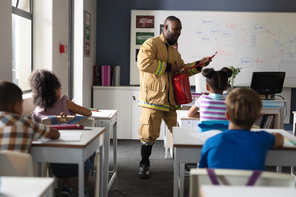 Bombeiro fazendo apresentação aos alunos em sala de aula, uma estratégia de educação inclusiva.