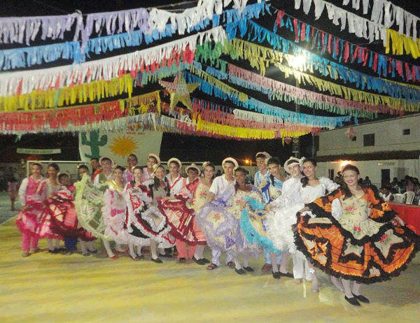 Pessoas dançando quadrilha com vestidos coloridos e rodados, uma alusão às curiosidades sobre a Festa Junina.