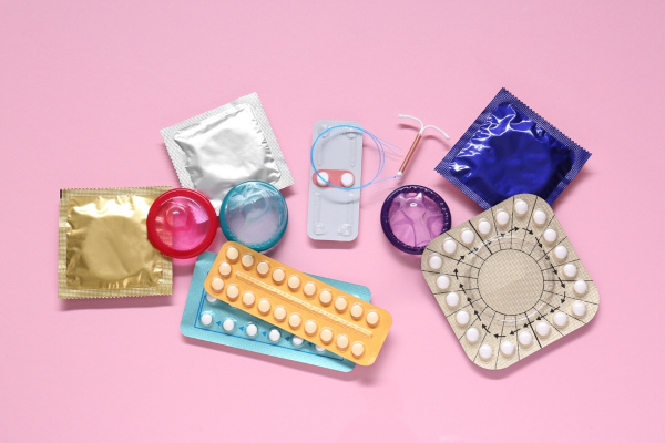 Diversos métodos contraceptivos sobre uma superfície plana cor-de-rosa.