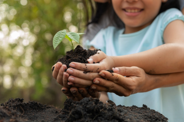 Criança plantando uma árvore junto de sua mãe, uma alusão à sustentabilidade, cuja ideia emergiu na Conferência de Estocolmo.