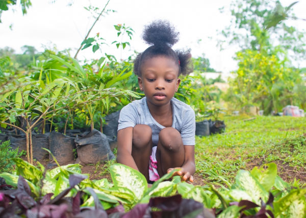 Menina negra plantando mudas, uma das opções de atividades para o Dia das Crianças. 