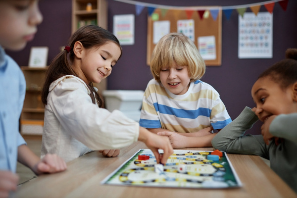 Crianças brincando com jogos de tabuleiro, uma dica de atividade para o Dia das Crianças.