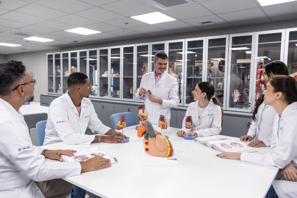 Professor ministrando aula à alunos em laboratório.
