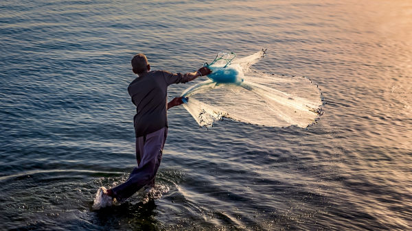 Pessoa praticando a pesca, tipo de extrativismo animal, uma das atividades do setor primário.