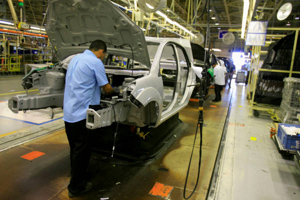 Pessoas trabalhando em linha de montagem da indústria automobilística, parte importante do setor secundário no Brasil.