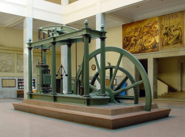 Motor de James Watt que revolucionou o sistema produtivo na Inglaterra, uma das invenções do século XVIII (18). Homem uma fábrica, uma alusão ao fato de que as primeiras fábricas surgiram no século XVIII (18).