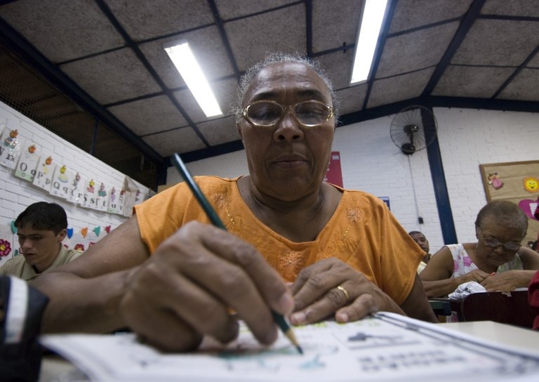 Mulher idosa realizando atividade da EJA. 