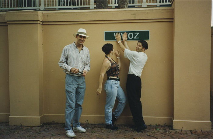 Trio vestindo blusas de cores neutras e jeans de corte reto e folgado em referência à moda dos anos 1990. 