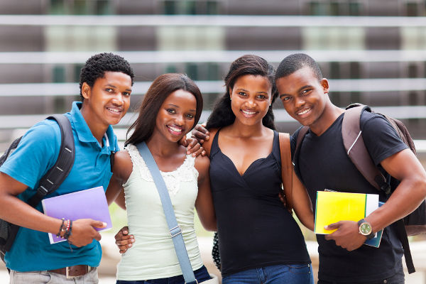 Quatro estudantes negros sorrindo com escada ao fundo