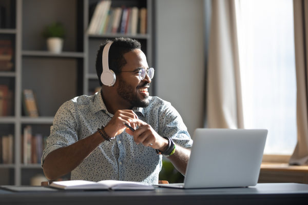 Homem negro com fone de ouvido sentado em frente ao computador