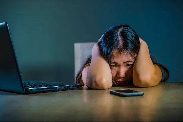 Menina com a mão na cabeça triste apoiada sobre uma mesa