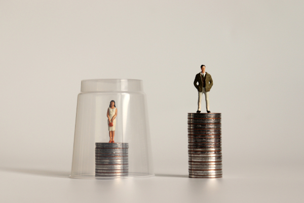 Homem e mulher sobre pilhas de moedas em tamanhos diferentes, em alusão à divisão sexual do trabalho.