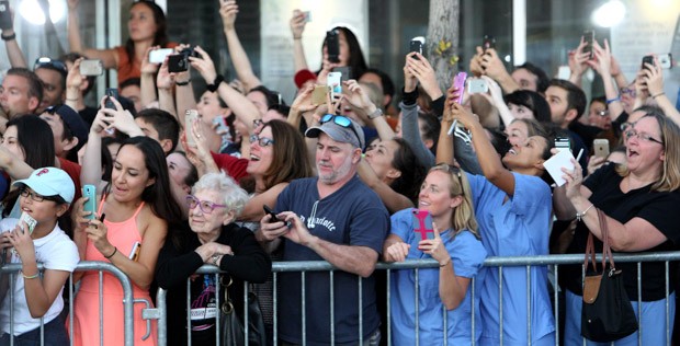 Senhora em meio a multidão de celulares e pessoas no registro feito pelo jornal The Boston Globe