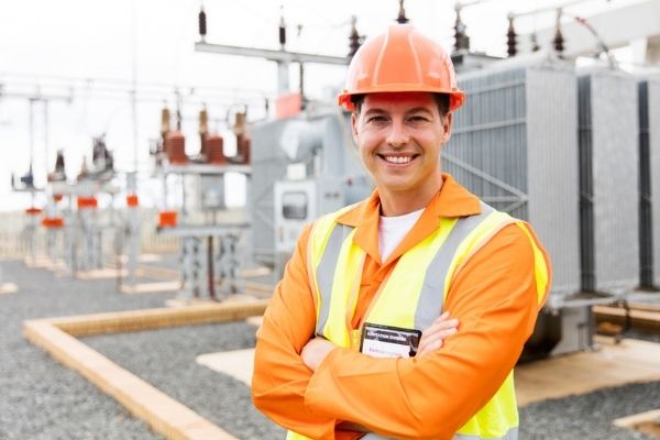 Engenheiro eletricista uniformizado com os braços cruzados sorrindo