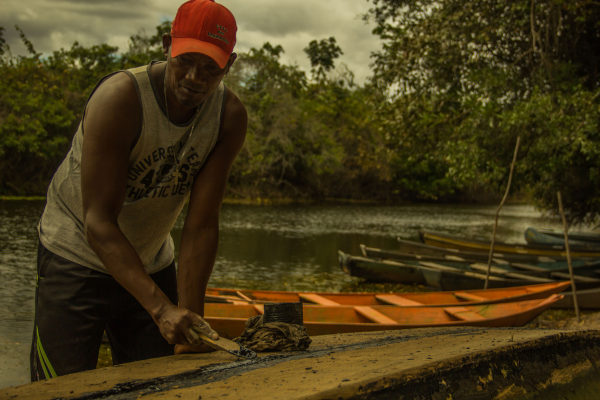 Homem negro próximo à canoa e rio