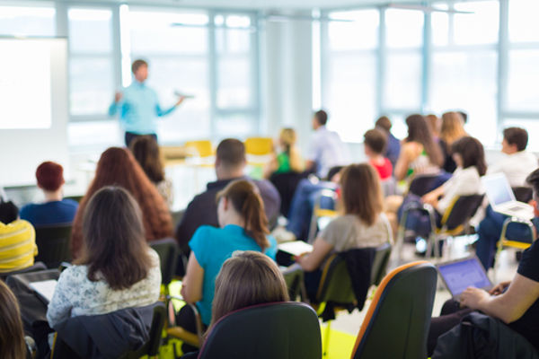 Imagem de sala de aula de um cursinho com professor e alunos